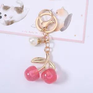 Close-up of pink glittery acrylic cherry keychain with gold metal clasp and pearl