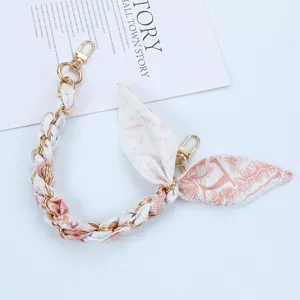 Close-up of elegant silk scarf phone chain with gold lobster clasps and floral pattern
