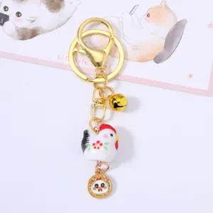 Detailed view of a cute ceramic chicken zodiac keychain with golden bell and charm