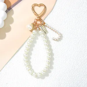 Close-up detail of elegant pearl keychain featuring golden heart clasp and pearl letter C charm
