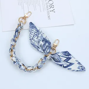 Close-up of blue and white patterned silk scarf phone strap with elegant golden chain
