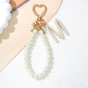 Detailed view of white pearl keychain with gold heart clasp and letter M charm