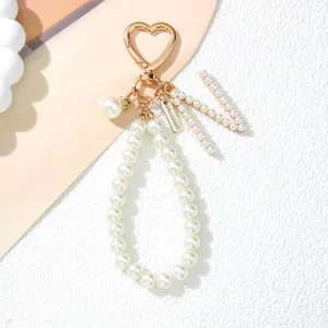 Close-up of elegant pearl keychain with gold heart clasp and pearl 'M' charm