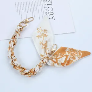 Detailed view of fashionable silk scarf phone strap with golden clasp and floral print