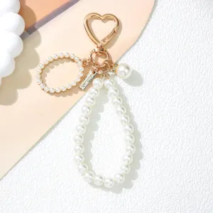 Close-up detail of a pearl keychain featuring a gold heart-shaped clip and elegant beaded charms