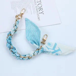 Detailed macro shot of light blue floral silk scarf phone lanyard chain with gold clasps
