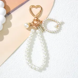 Close-up detail of a pearl-beaded keychain featuring a heart clasp and initial S charm