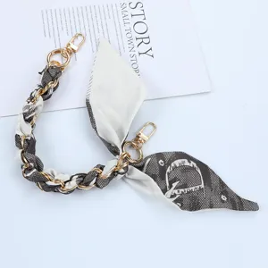 Detailed view of a short phone strap featuring a gold chain and patterned silk scarf