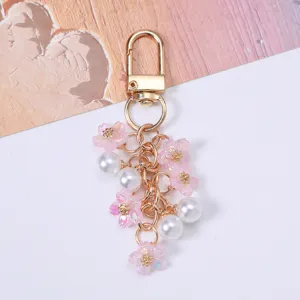 Detailed view of sweet pink cherry blossom and white pearl keychain with gold metal clasp