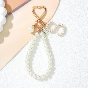 Close-up of pearl letter S keychain with gold heart buckle and handmade metal tag