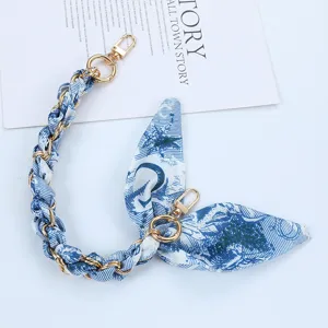 Close-up of blue and white silk scarf phone strap with gold chain and double clasps.