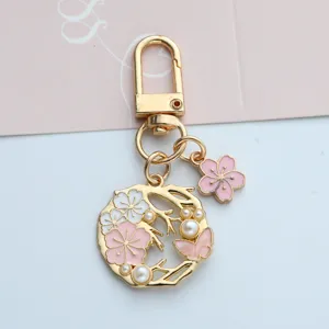 Detailed macro view of an elegant gold-toned cherry blossom keychain with pearls.