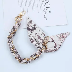 Detail view of gold chain phone strap interwoven with decorative printed silk scarf