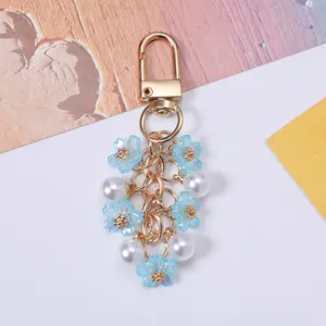 Macro view of floral keychain featuring blue cherry blossoms and elegant white pearls