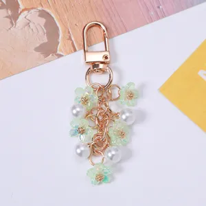 Detailed view of sweet green cherry blossom and pearl keychain with gold-toned metal clasp.