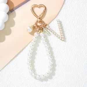 Detailed view of white pearl keychain with heart clasp and letter V charm