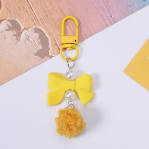 Adorable yellow resin bow keychain with elegant pearls and fluffy pompom detail