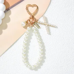 Detailed view of a pearl keychain with heart clip and a letter X charm pendant.