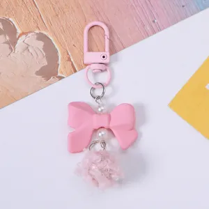 Detailed view of a cute pink resin bow keychain featuring a soft plush ball and pearls.