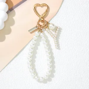 Close-up of pearl letter Y keychain with gold heart clasp and white pearl strap