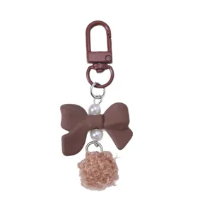 Cute brown resin bow keychain featuring a fuzzy pom-pom and elegant pearl accents