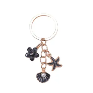 Elegant gold alloy keychain featuring black starfish and shell charms with a pearl accent.