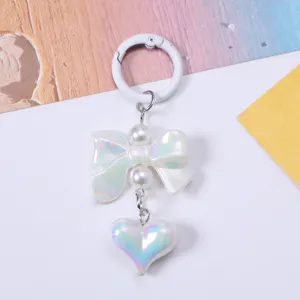 Detailed view of iridescent heart and bow keychain charm with elegant pearl accents