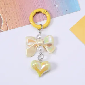 Close-up of cute pearlescent heart and bow charm keychain with yellow spring hook