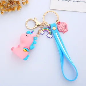 Detail showing pink unicorn keychain with blue strap, rainbow and shell charms.
