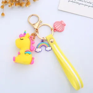 Detailed close-up of a cute yellow unicorn keychain featuring rainbow and shell charms