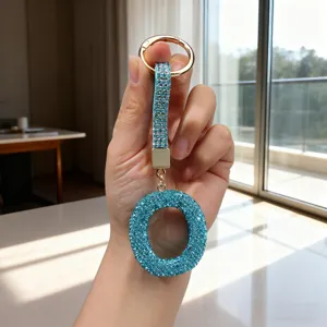 Macro detail of a sparkling blue rhinestone letter O keychain held by hand in light