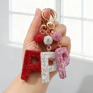 Gros plan de trois porte-clés lettre P incrustés de strass en rouge, argent et rose