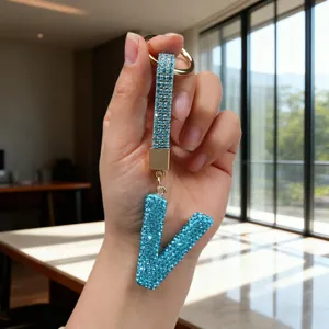 Close-up of a blue rhinestone-studded letter V keychain with gold-tone hardware