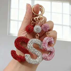Gros plan de porte-clés lettre 'S' étincelants en strass, couleurs rouge, argent et rose