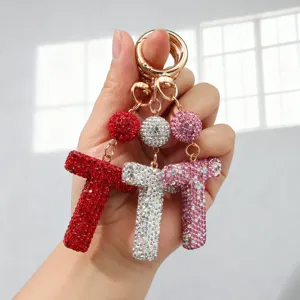 Gros plan de porte-clés lettre T incrustés de strass étincelants en rouge, argent et rose.