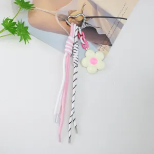 Close-up of heart-shaped keychain with braided ropes and white flower charm detail