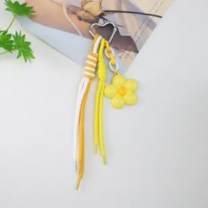 Close-up of heart-shaped alloy keychain with yellow flower pendant and woven cords