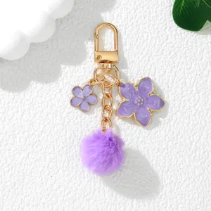 Close-up of a purple cherry blossom keychain with a fluffy pom-pom and gold alloy hook