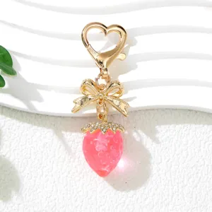 Detailed macro view of cute pink UV strawberry keychain with gold bow and heart clasp