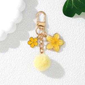 Detail view of Japanese style yellow flower keychain with soft pompom and gold hardware