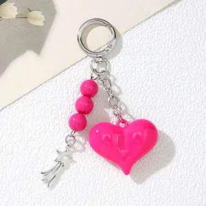 Macro view of bright pink acrylic heart pendant and silver star charm keychain