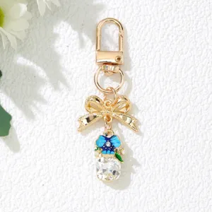 Détail d'un porte-clés doré avec nœud papillon, fleur bleue et grand cristal brillant