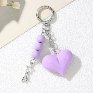 Close-up detail showing the purple acrylic heart keychain with beads and star charm.