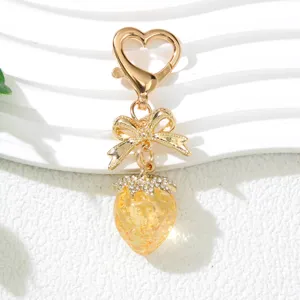 Close-up of cute UV plated strawberry keychain with golden bow and heart clasp