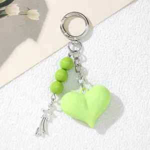 Detailed macro view showing the glossy green acrylic heart and silver star charm of the keychain