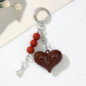 Macro view of dark brown heart keychain featuring red beads and a silver star charm