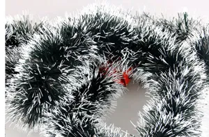 Close-up of dark green Christmas tinsel garland with snowy white tips for decoration