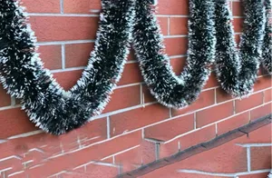 Detailed view of 2-meter dark green Christmas tinsel garland with white snow-tipped edges.