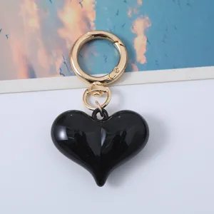 Close-up shot of a glossy black acrylic heart keychain with gold hardware detailing