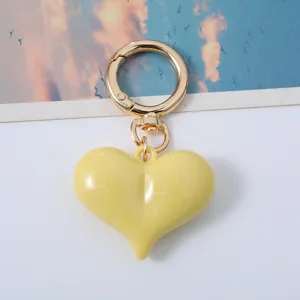Close-up of a glossy yellow heart-shaped acrylic keychain with a gold carabiner clasp.